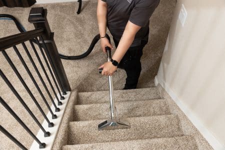 maid from Vetter Cleaners of Colorado Springs vacuuming carpeted stairs