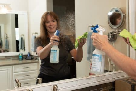 a maid from Vetter Cleaning of Colorado Springs, CO cleaning a bathroom mirror