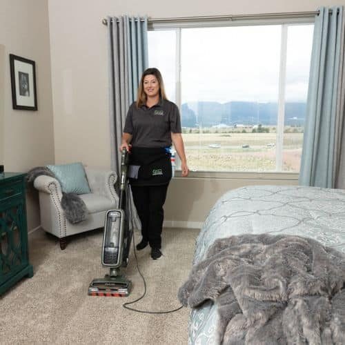 a maid from Vetter Cleaning of Colorado Springs vacuuming a bedroom during a deep cleaning service